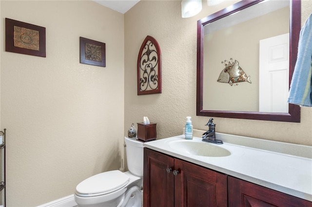 half bathroom with vanity, a textured wall, and toilet