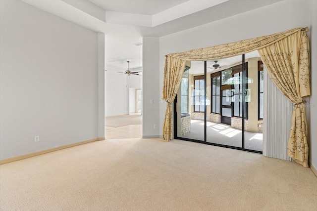 carpeted empty room featuring a ceiling fan and baseboards