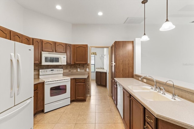 kitchen featuring decorative backsplash, hanging light fixtures, a sink, light countertops, and white appliances