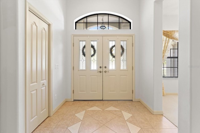 foyer featuring a healthy amount of sunlight, light tile patterned floors, and baseboards