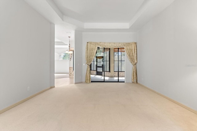 carpeted empty room featuring baseboards and a raised ceiling