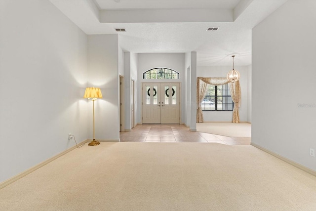 carpeted entryway featuring visible vents, baseboards, tile patterned flooring, and a notable chandelier