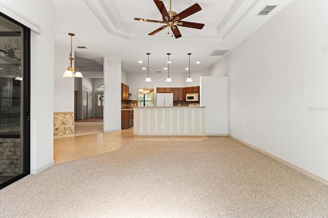 unfurnished living room featuring visible vents, light colored carpet, recessed lighting, a raised ceiling, and a ceiling fan