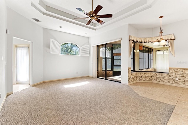 spare room with tile patterned flooring, ceiling fan, a tray ceiling, and visible vents