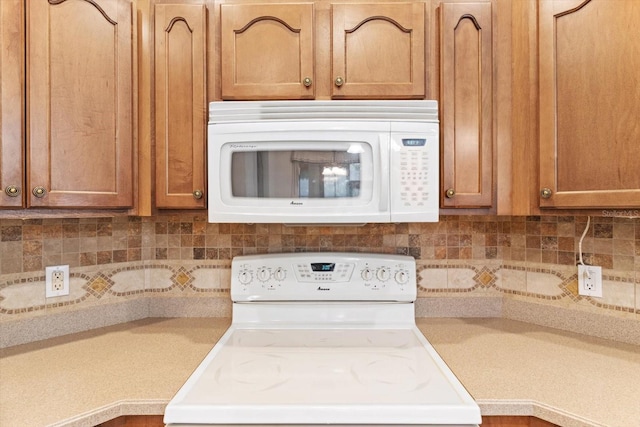 kitchen featuring light countertops, brown cabinets, white appliances, and tasteful backsplash