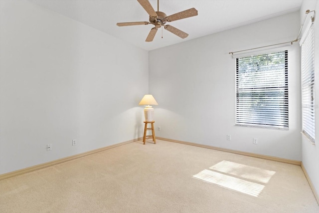 carpeted empty room featuring baseboards and ceiling fan