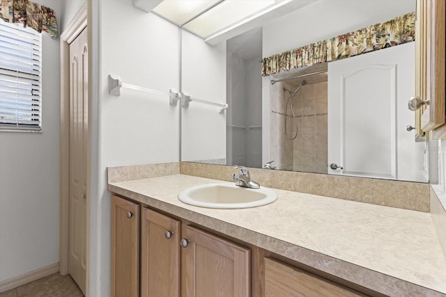 bathroom featuring vanity, baseboards, and a tile shower