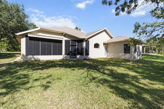 rear view of house with a lawn, stucco siding, and a sunroom