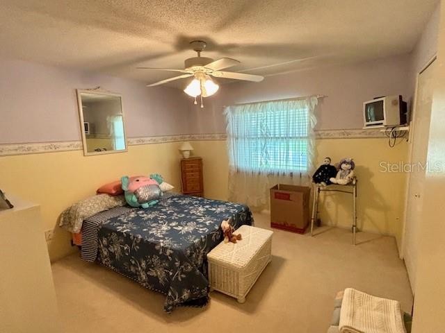 4145 SE 3rd St, Ocala, FL 34471 - bedroom featuring carpet floors, a ceiling fan, and a textured ceiling