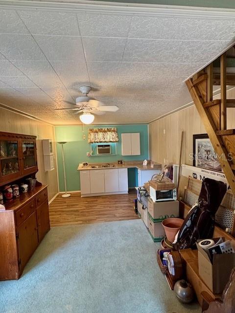 4145 SE 3rd St, Ocala, FL 34471 - kitchen featuring wooden walls, ceiling fan, light carpet, and white cabinetry