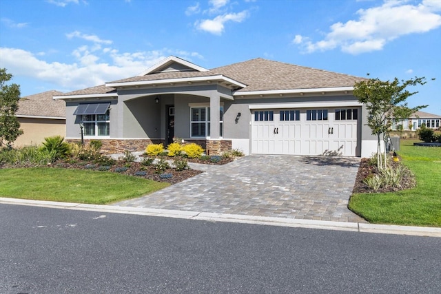 view of front of property with a front yard, decorative driveway, an attached garage, stone siding, and stucco siding