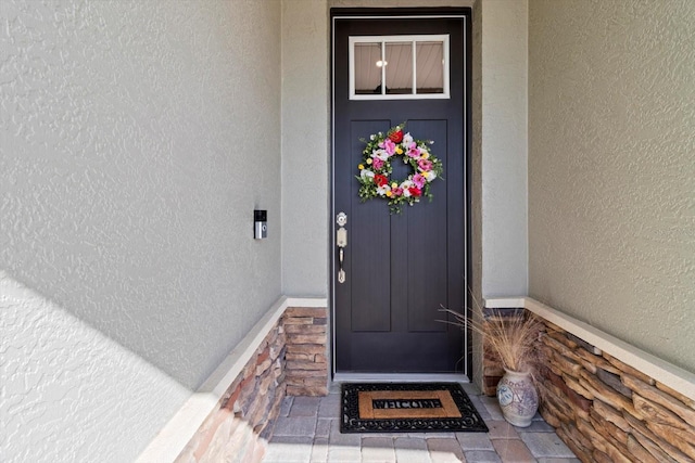 doorway to property with stucco siding and stone siding