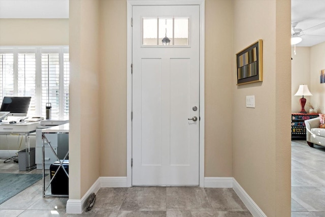 entryway featuring ceiling fan, a healthy amount of sunlight, and baseboards