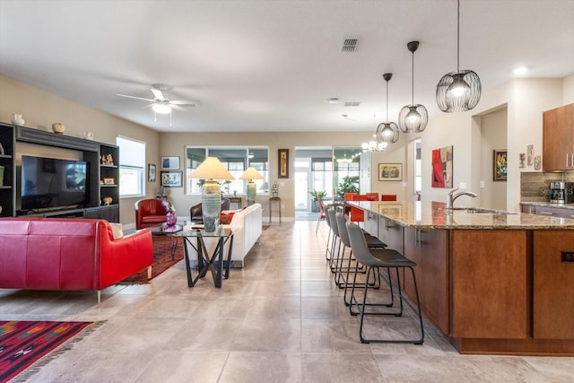 interior space with light tile patterned floors, ceiling fan with notable chandelier, and visible vents