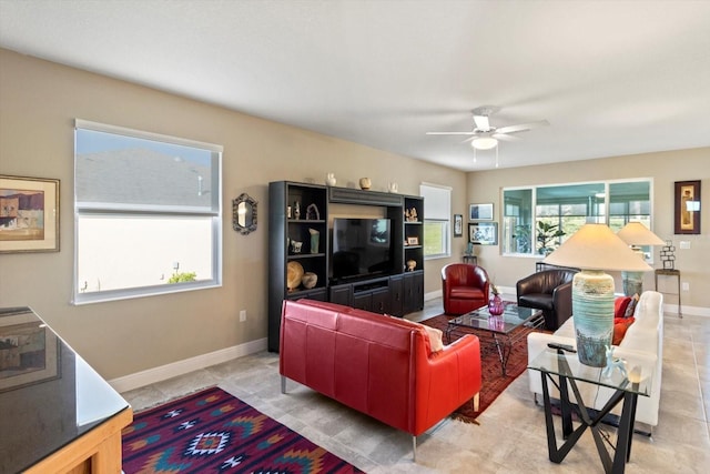 living room with baseboards, ceiling fan, and a healthy amount of sunlight