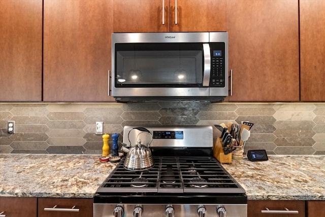 kitchen featuring stainless steel appliances, light stone countertops, and decorative backsplash