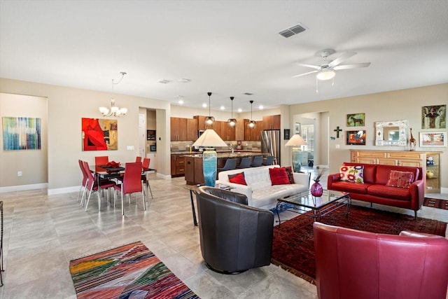living room with visible vents, baseboards, and ceiling fan with notable chandelier