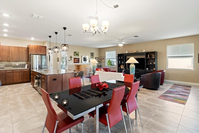 dining space featuring baseboards, visible vents, light tile patterned floors, and ceiling fan with notable chandelier