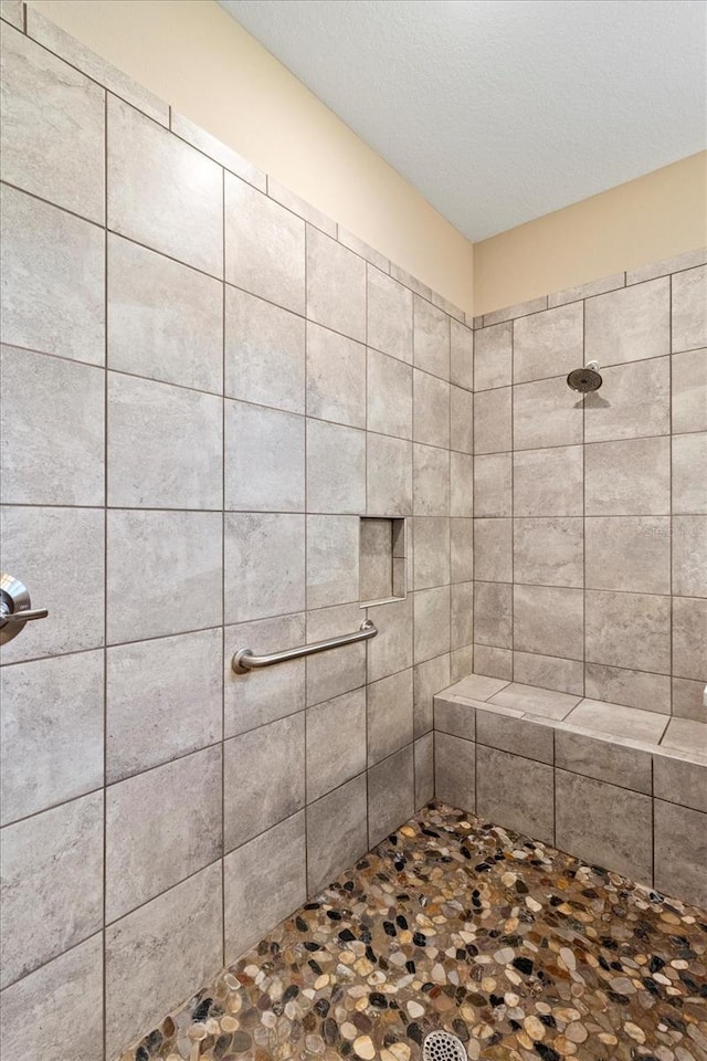 bathroom featuring a textured ceiling and a tile shower