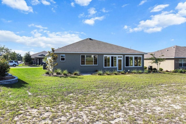 back of property with a yard and stucco siding