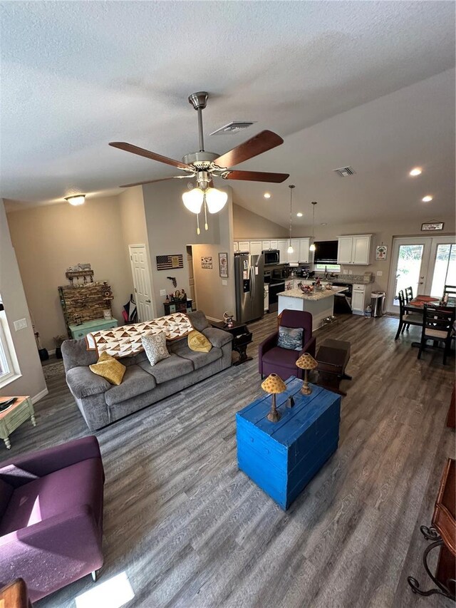 living room with a ceiling fan, a textured ceiling, visible vents, lofted ceiling, and dark wood-type flooring