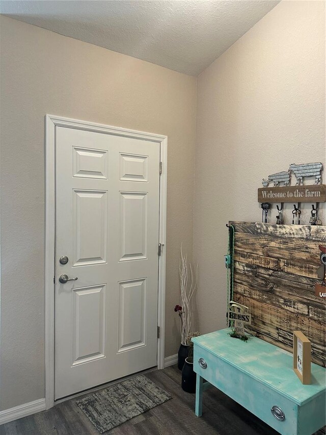 interior space with a textured ceiling, baseboards, and wood finished floors