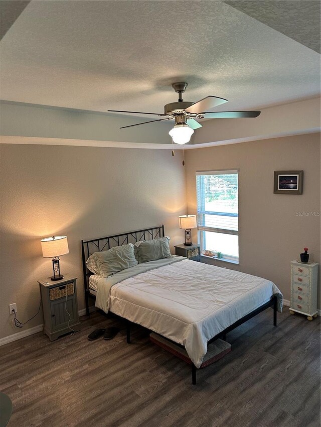 bedroom featuring baseboards, ceiling fan, dark wood-style flooring, and a textured ceiling