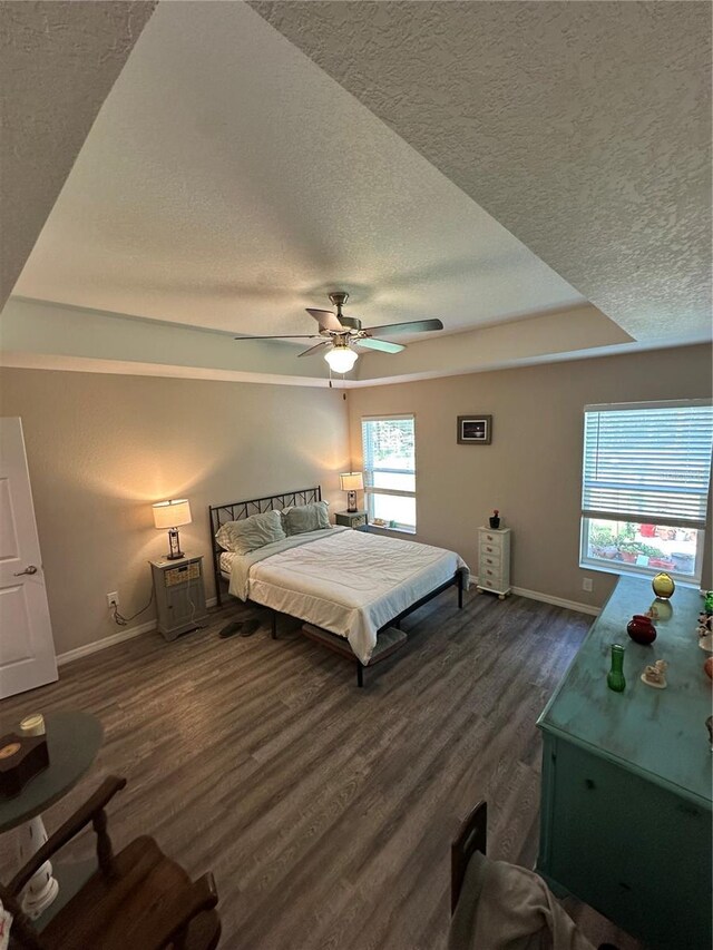 bedroom with baseboards, ceiling fan, a textured ceiling, and wood finished floors