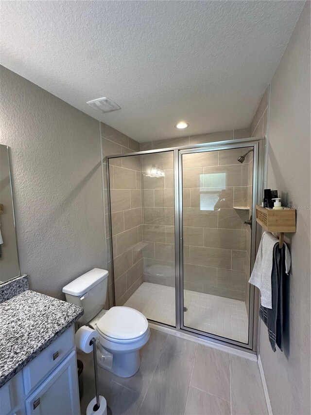 bathroom featuring toilet, a textured ceiling, a shower stall, and vanity