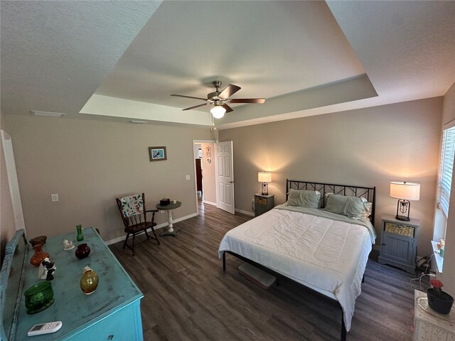 bedroom featuring a raised ceiling, baseboards, ceiling fan, and dark wood-type flooring