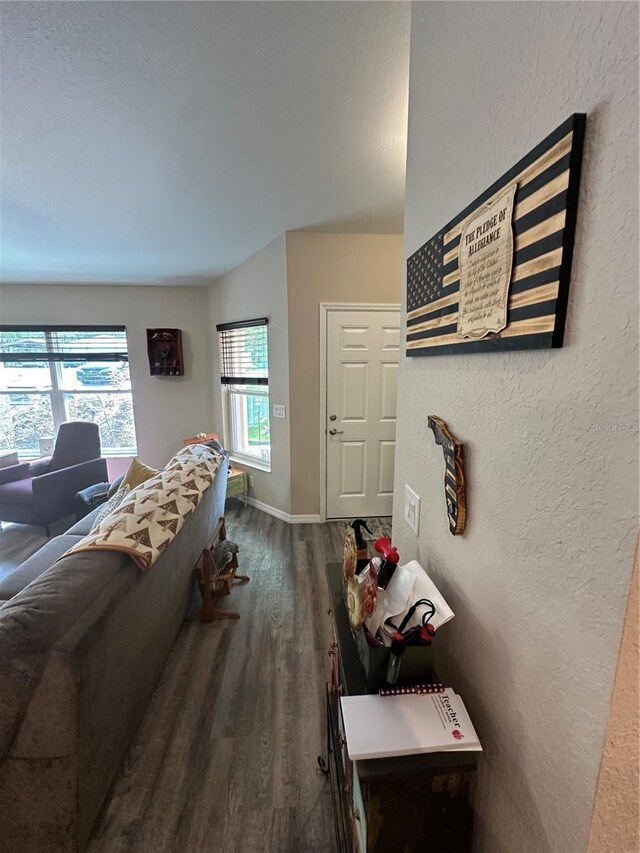living area featuring baseboards, a textured wall, and wood finished floors