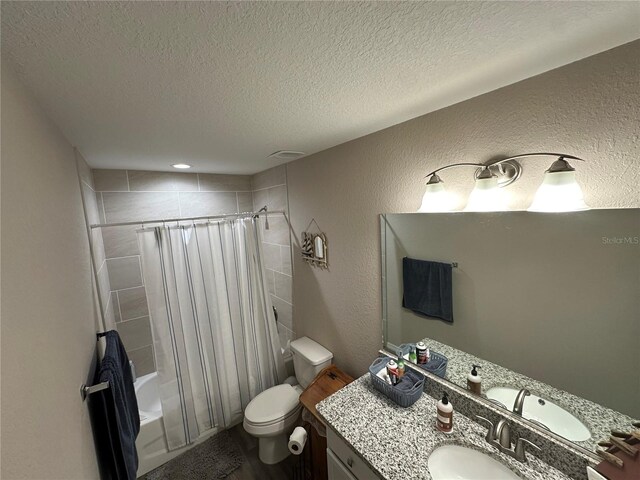 full bathroom with vanity, shower / tub combo with curtain, a textured wall, toilet, and a textured ceiling