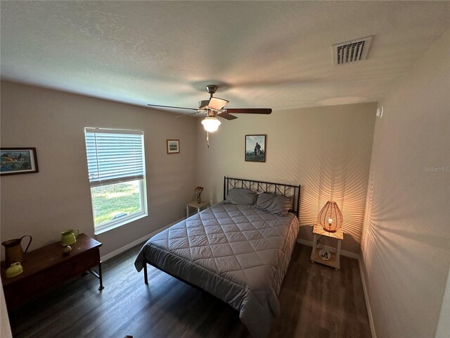 bedroom featuring visible vents, a ceiling fan, baseboards, and wood finished floors