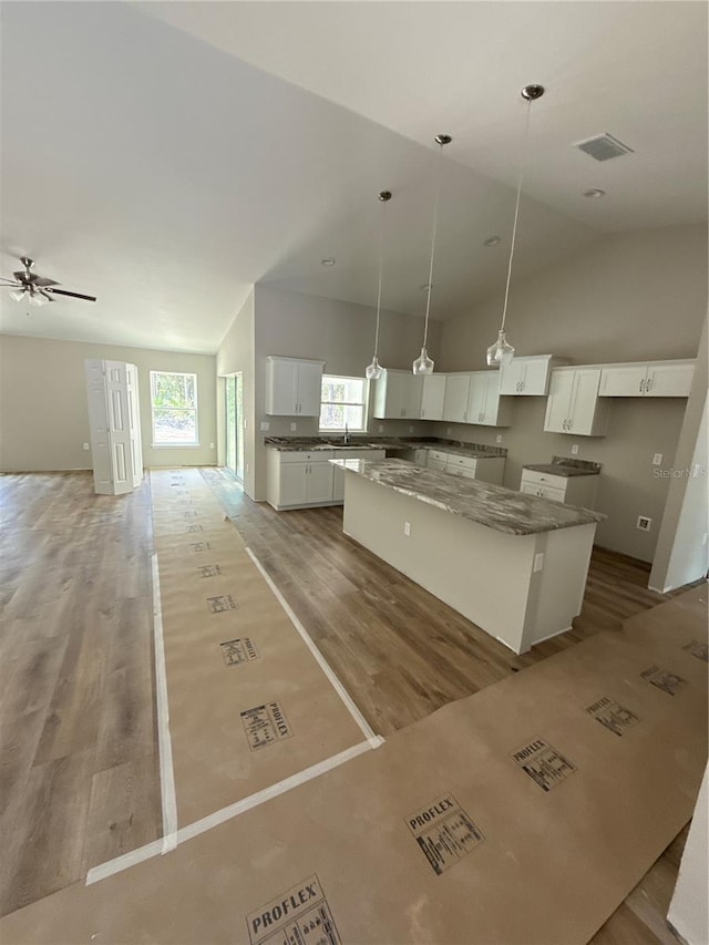 kitchen featuring a kitchen island, light wood-style floors, open floor plan, white cabinets, and a sink