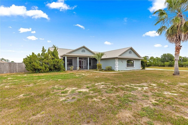 6045 SE 99th Pl, Belleview, FL 34420 - ranch-style home with a front yard, fence, metal roof, and a sunroom