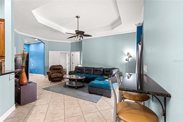 6045 SE 99th Pl, Belleview, FL 34420 - living area with crown molding, ceiling fan, a tray ceiling, arched walkways, and light tile patterned floors