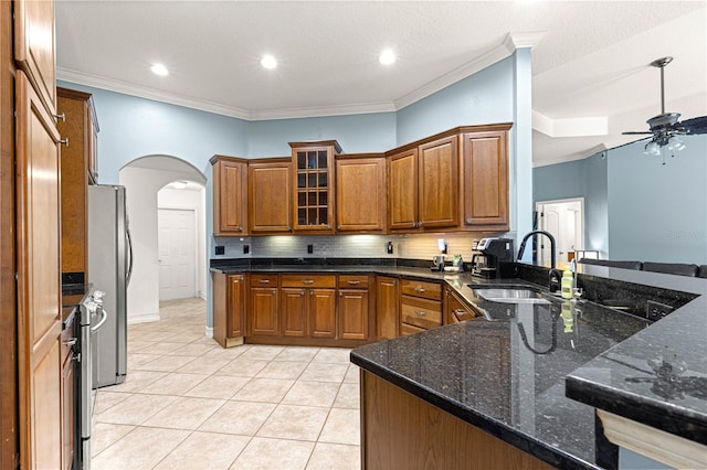 6045 SE 99th Pl, Belleview, FL 34420 - kitchen with ceiling fan, arched walkways, brown cabinets, a sink, and light tile patterned floors