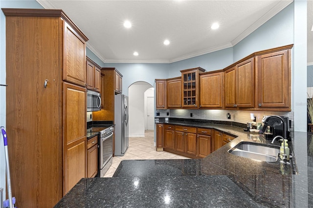6045 SE 99th Pl, Belleview, FL 34420 - kitchen featuring brown cabinets, a sink, arched walkways, stainless steel appliances, and backsplash