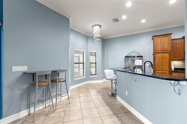 6045 SE 99th Pl, Belleview, FL 34420 - kitchen featuring crown molding, a chandelier, brown cabinetry, a kitchen bar, and visible vents
