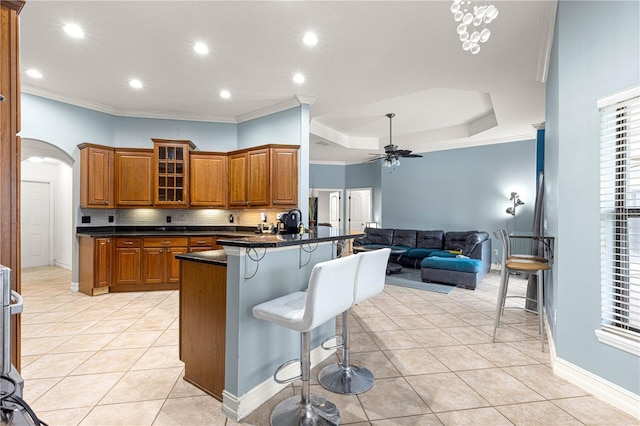 6045 SE 99th Pl, Belleview, FL 34420 - kitchen featuring ceiling fan, a breakfast bar area, brown cabinetry, dark countertops, and open floor plan
