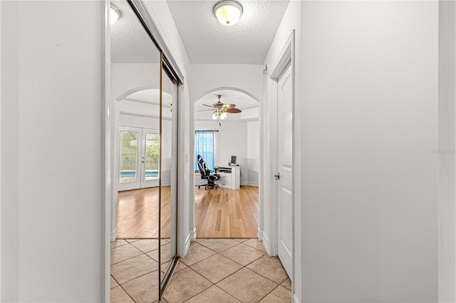 6045 SE 99th Pl, Belleview, FL 34420 - hallway featuring arched walkways, french doors, a textured ceiling, and light tile patterned flooring