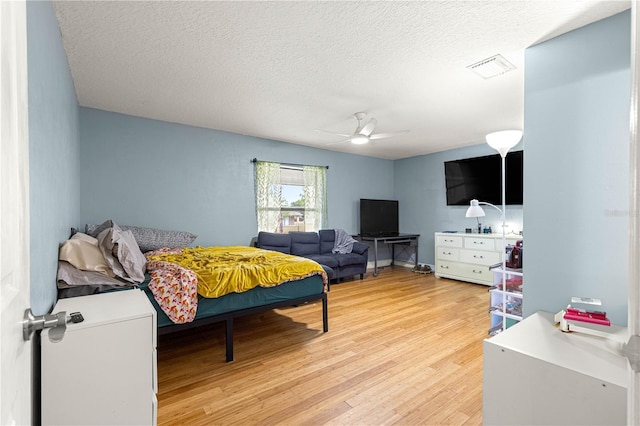 6045 SE 99th Pl, Belleview, FL 34420 - bedroom with ceiling fan, light wood-type flooring, a textured ceiling, and visible vents