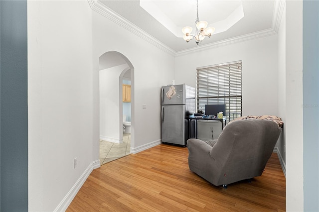 6045 SE 99th Pl, Belleview, FL 34420 - sitting room featuring arched walkways, a raised ceiling, an inviting chandelier, ornamental molding, and light wood-style flooring