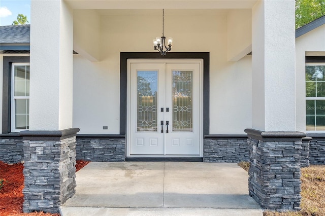 doorway to property featuring french doors, stucco siding, and stone siding