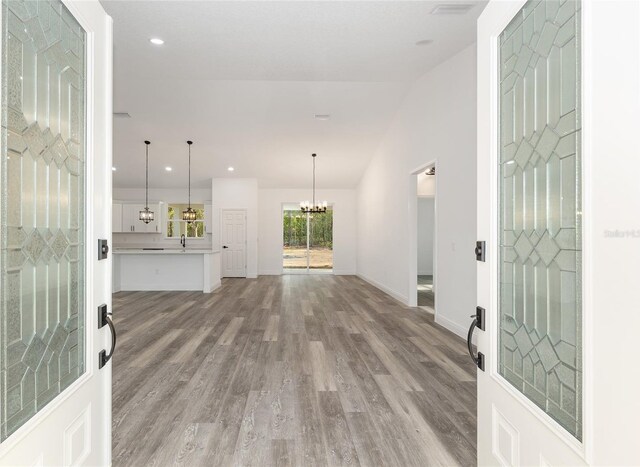 foyer with recessed lighting, baseboards, a notable chandelier, and wood finished floors