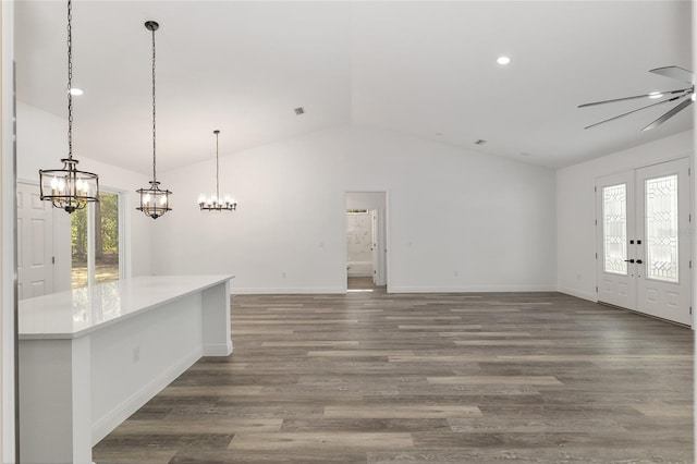 unfurnished living room with french doors, vaulted ceiling, wood finished floors, baseboards, and a chandelier