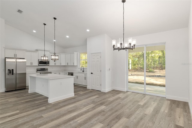 kitchen with white cabinets, appliances with stainless steel finishes, light countertops, a chandelier, and a kitchen island