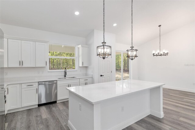 kitchen with stainless steel dishwasher, wood finished floors, a sink, light countertops, and an inviting chandelier