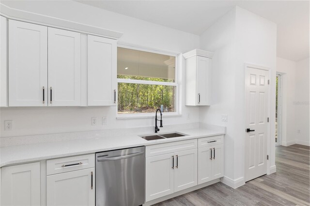 kitchen featuring dishwasher, a sink, light countertops, light wood-style floors, and white cabinetry