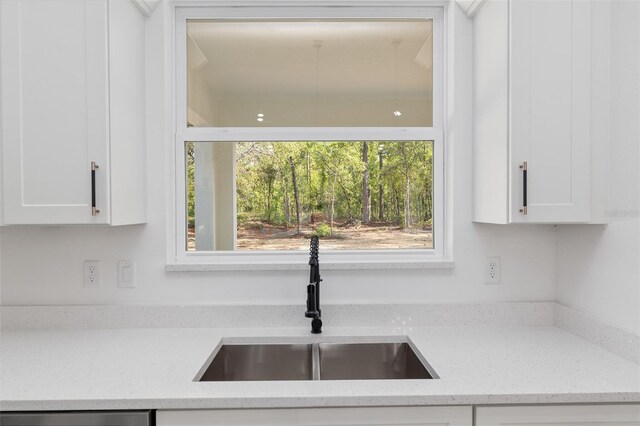 kitchen featuring white cabinetry, light stone countertops, a sink, and dishwasher